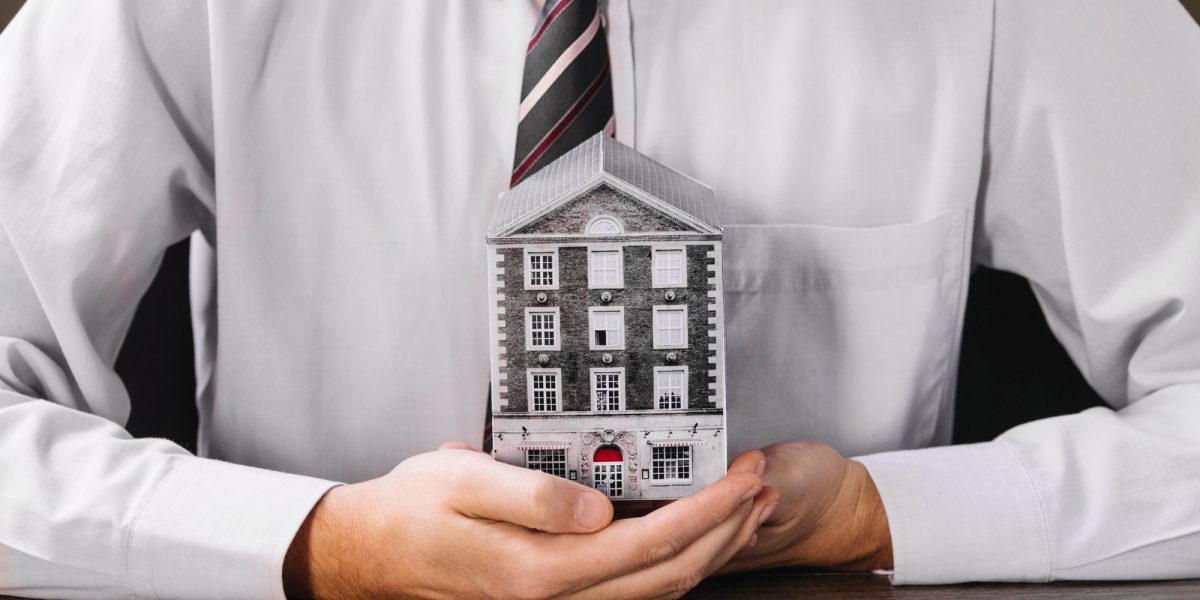 man-holding-miniature-house-hands